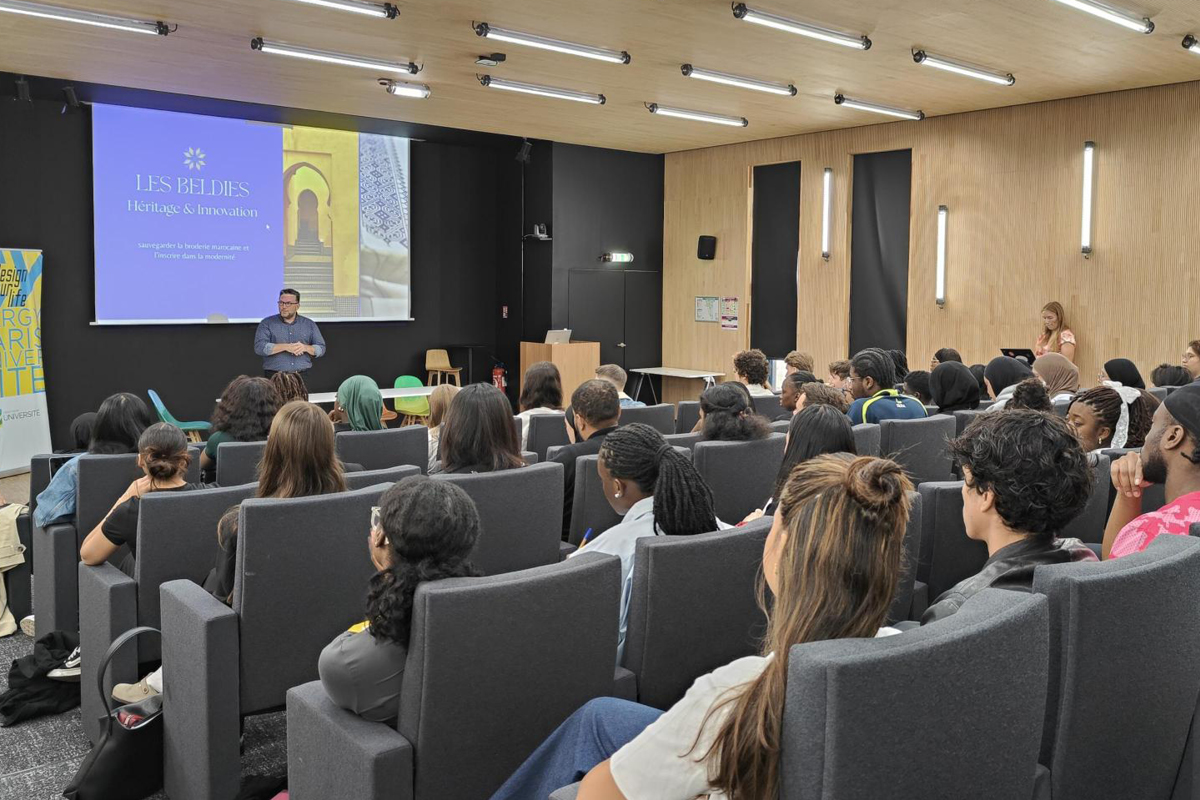 Des étudiantes et des étudiants sont assis dans amphithéâtre plein. Ils écoutent l'intervention de l'enseignant
