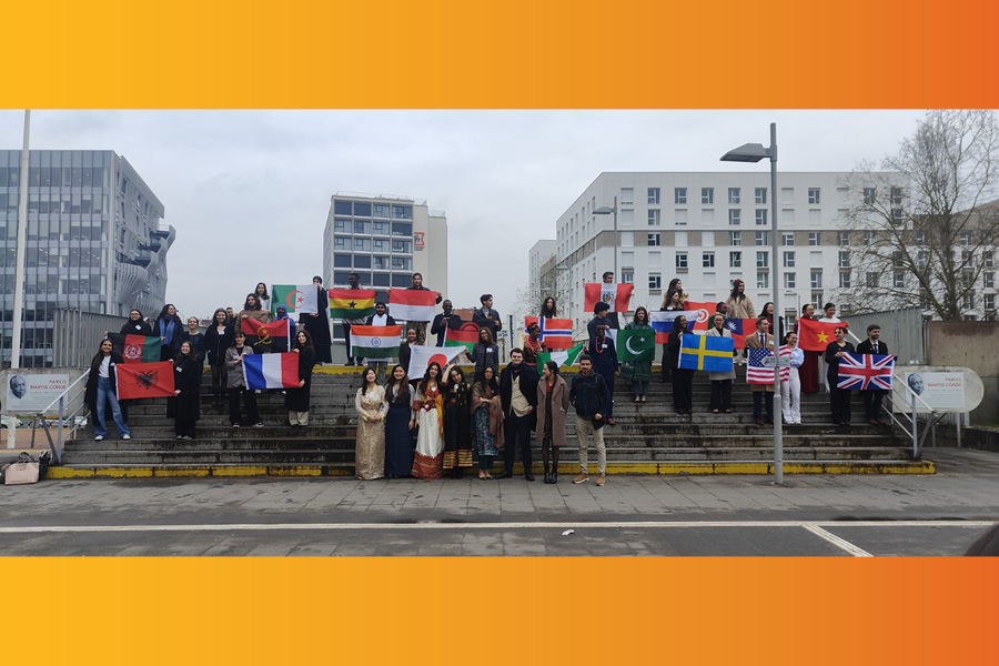 Des étudiantes habillées en différentes tenues traditionnelles lèvent des drapeaux de différents pays face à eux