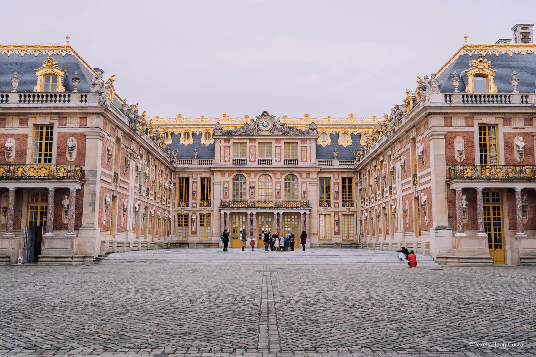 Un groupe de tourisme marche devant l'entrée principale de Versailles