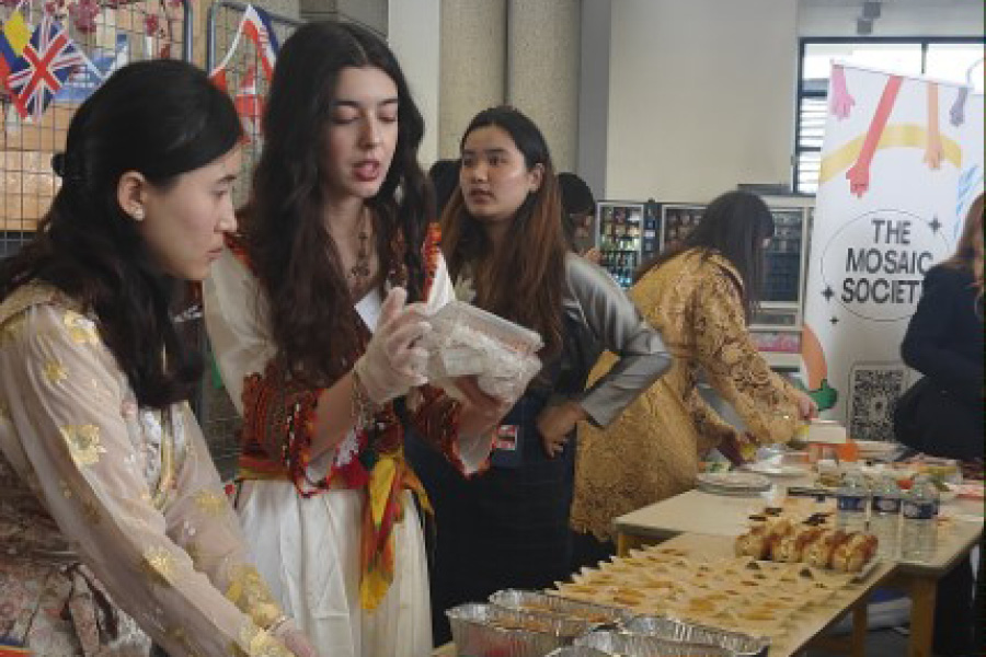 Des étudiantes habillées en différentes tenues traditionnelles servent un buffet